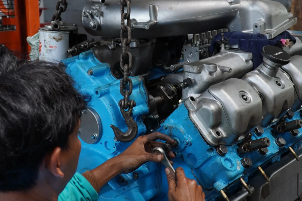 Teknisi memeriksa pemasangan dan alignment mesin kapal diesel untuk mencegah kerusakan saat penggantian mesin